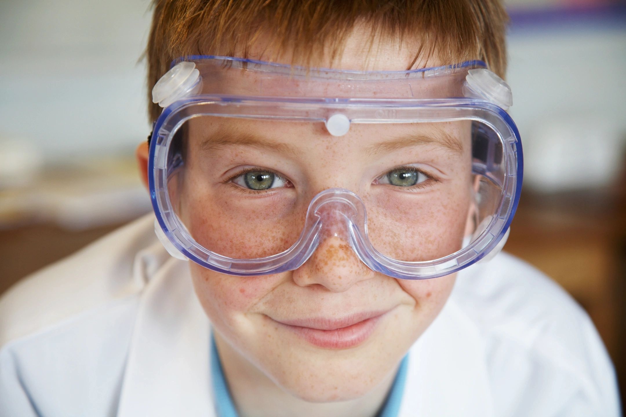 A young boy wearing goggles and lab coat.